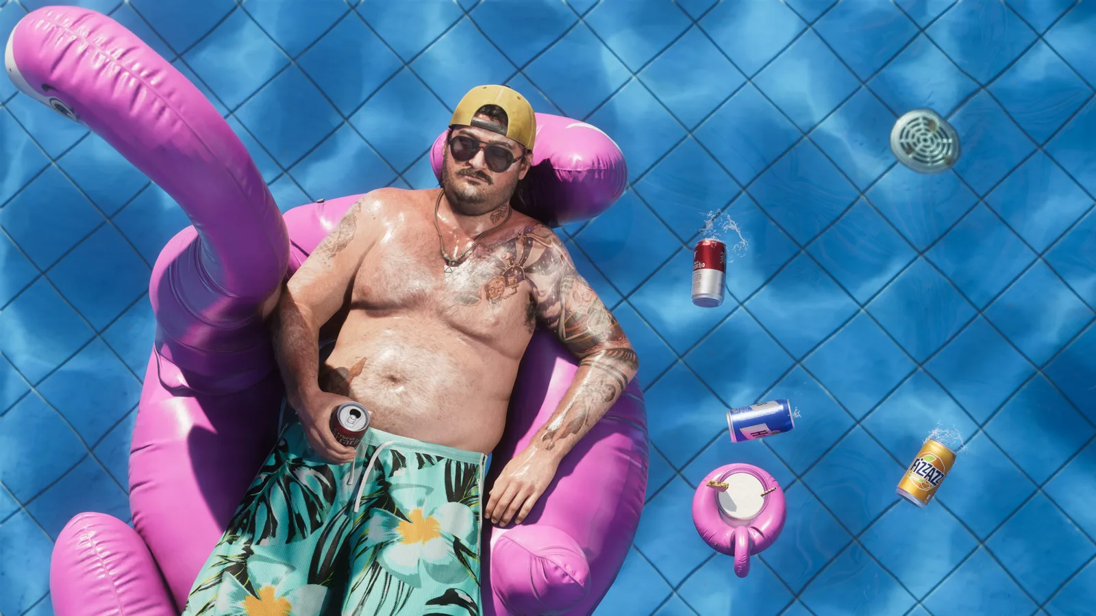 Overhead view of Cal Hampton in a backwards cap and sunglasses floating on a pink flamingo pool inflatable, drink cans and a floating ashtray on the water around him.