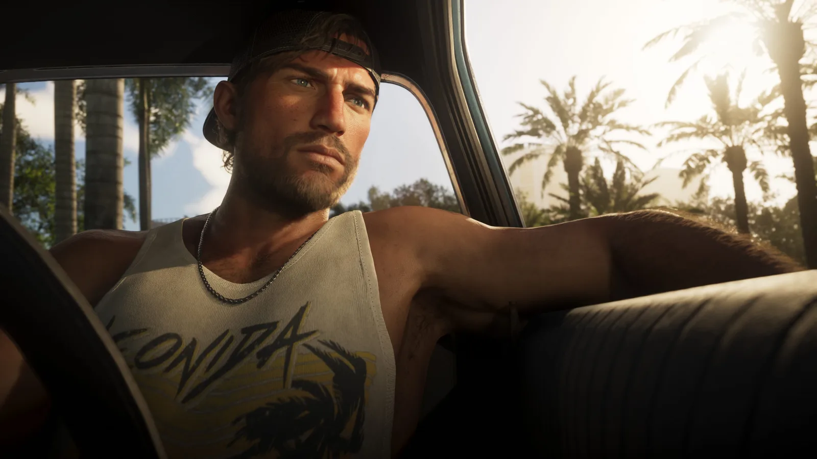 Jason Duval in a backwards cap and a Leonida tank top, sitting in a car with one arm over the seat back, sunlit palms through the window behind him.