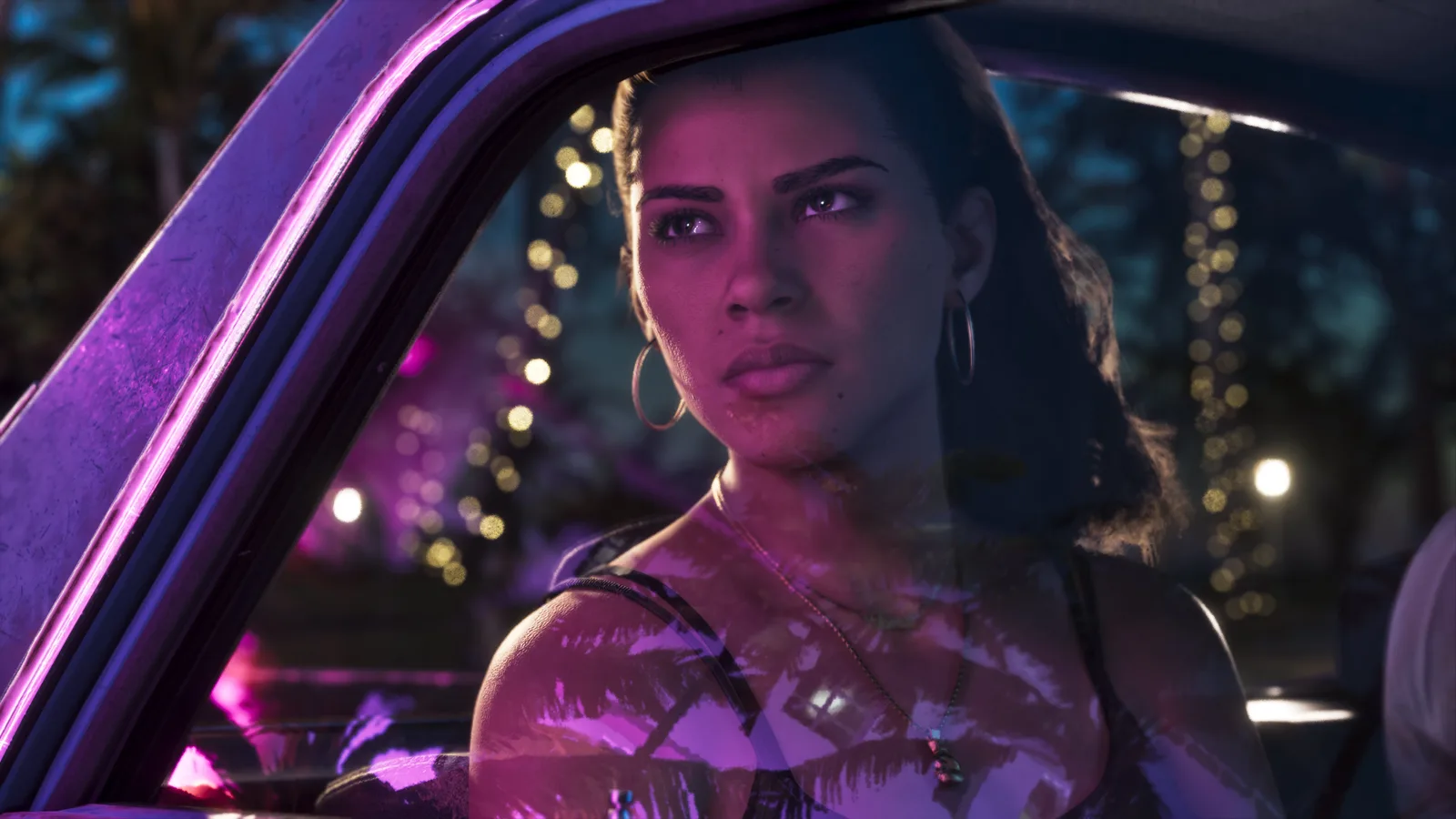 Lucia Caminos in the passenger seat of a car at night, looking off to the side, string lights and neon reflected across the windscreen.