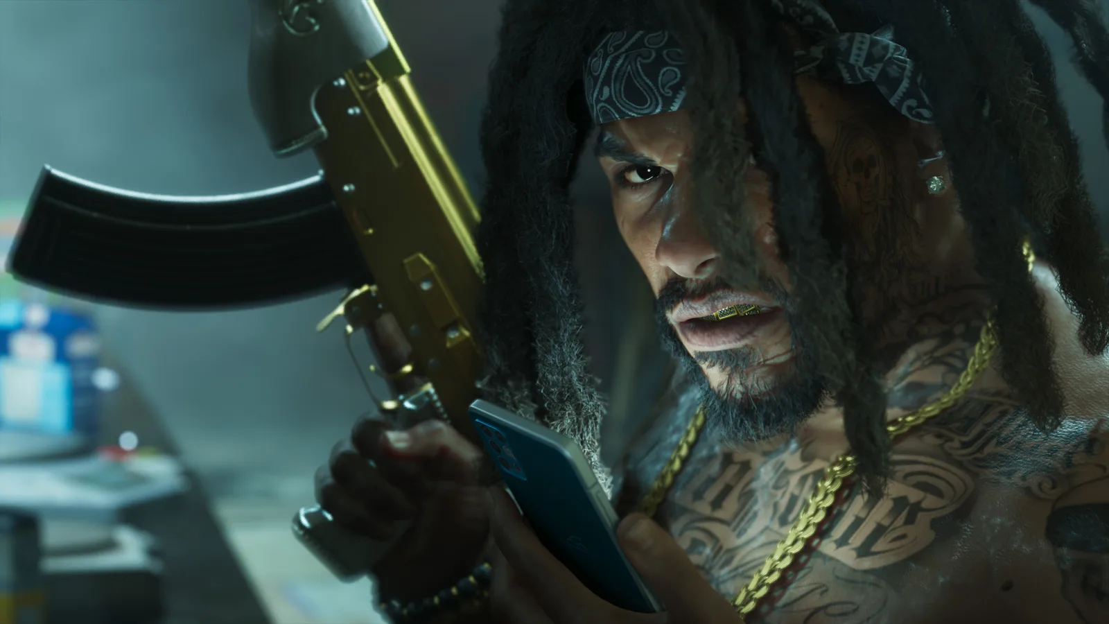 Close-up of a man in a hood and paisley bandana with long locs, gold chains and a gold grill, holding a gold-finished assault rifle in one hand and looking at a phone in the other.
