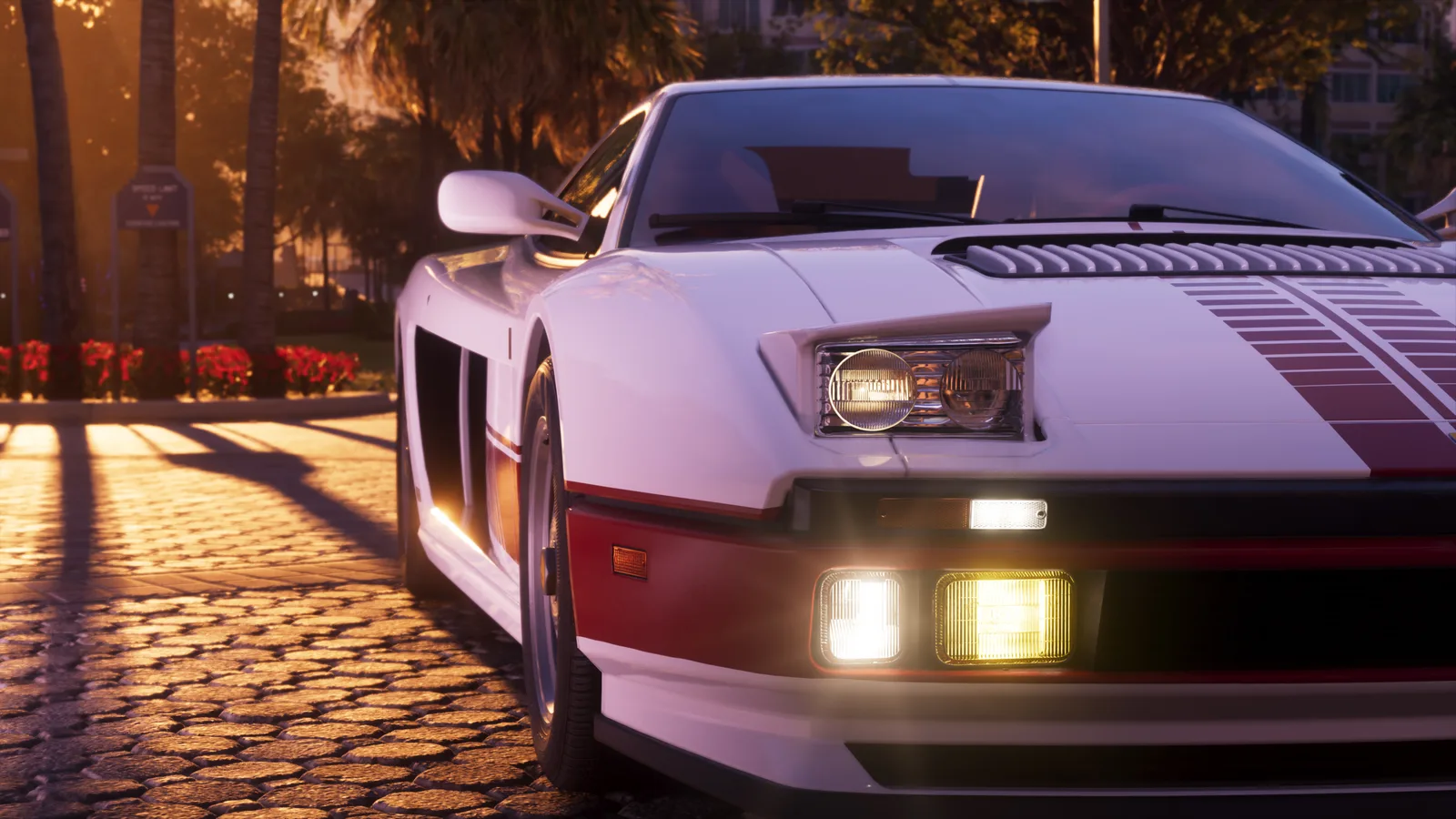 Front three-quarter close-up of the white Grotti Cheetah at golden hour with a pop-up headlight raised and its fog lamps lit, parked on cobbles beside palms and a flowerbed.