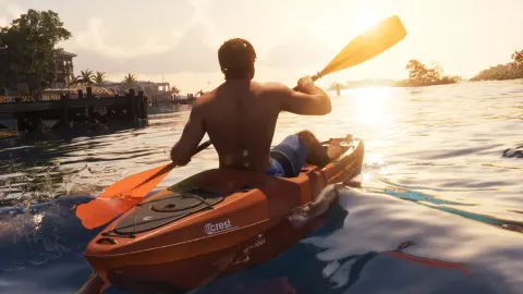 A paddler in an orange Crest kayak on calm water at sunset.