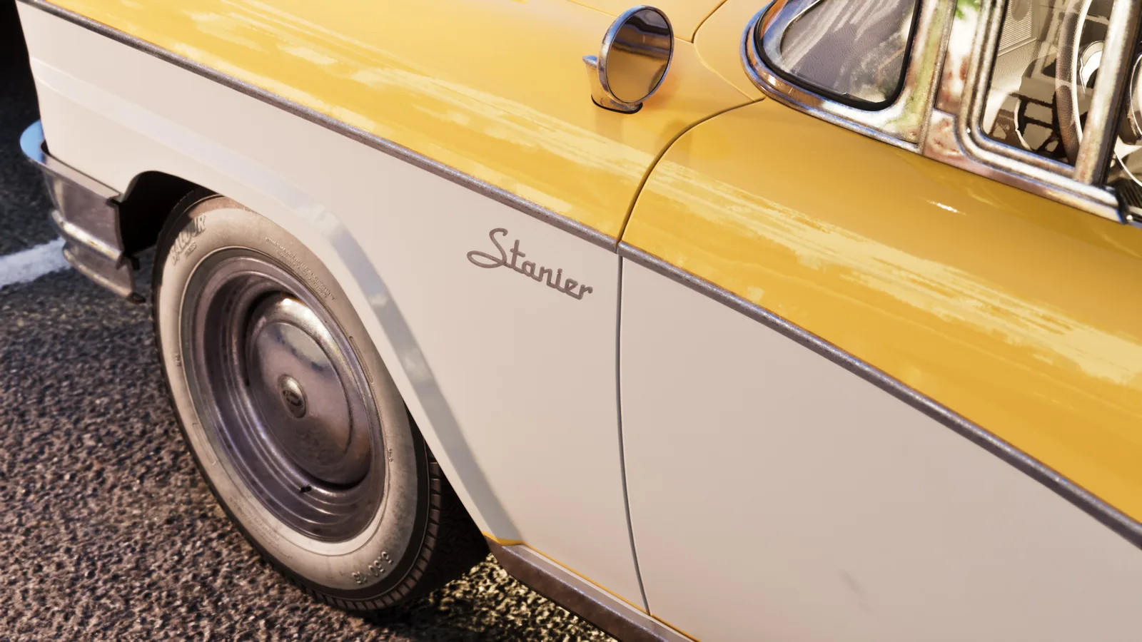Close-up of the Stanier's yellow-over-cream flank in sunlight, a Stanier script badge on the front wing above a chrome hubcap and whitewall tyre.